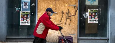 Getty Images Man walking outside a boarded-up shop in Newport