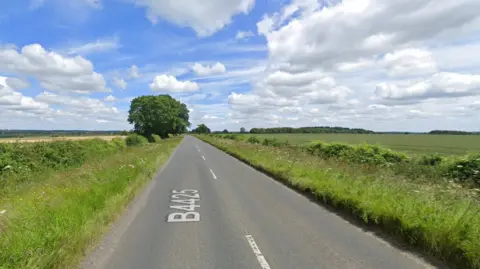 Google image of a strip of the B4425. It is a long, straight stretch of road with fields and hedges to either side of the carriageway. Google's 'B4425' text is shown on the road.