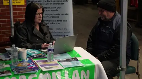 A Macmillan Cancer nurse sits down with a fisherman and discusses cancer support at North Shields Fish Quay. 
