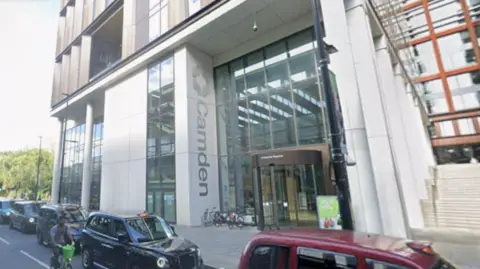 Google The exterior of Camden Council’s headquarters is shown from street level, with large glass panels, the Camden logo on a white column and traffic passing in front of the building.