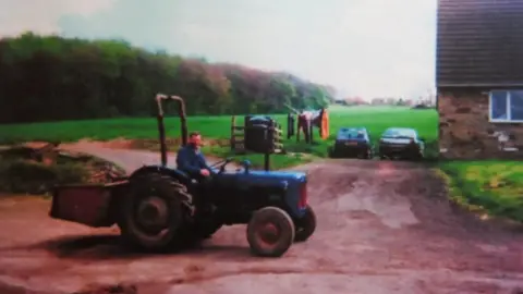 PA Media Handout photo showing John Charlesworth driving a blue tractor.