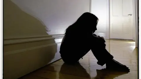 Getty Images A silhouette of a woman sitting in the hallway. 