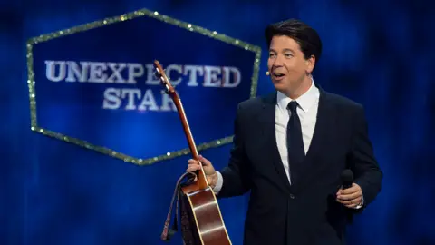 Michael McIntyre holding a guitar while presenting Michael McIntyre's big show