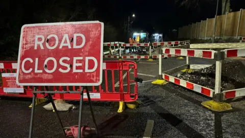 Road showing closure signs and machinery/building work