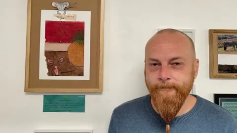 Arc Mark in front of his artwork