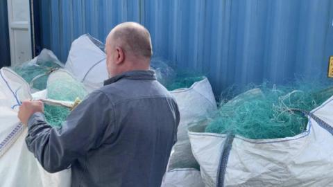 Man in front of bags filled with old nets