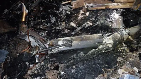 London Fire Brigade A burnt out e-scooter surrounded a mess of unrecognisable debris. Very little is left of the metal scooter.