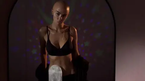 Lime Pictures/Channel 4 Hollyoaks character Mercedes McQueen played by actress Jennifer Metcalfe is seen without any hair, with a chemotherapy port on her chest and a stoma bag attached to her stomach 