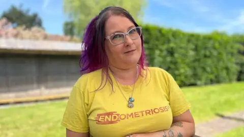 A woman with pink hair and a yellow t-shirt