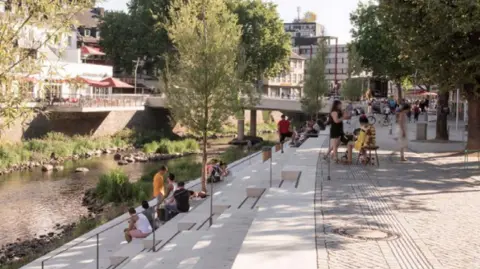 Martin Randelhoff – Creative Commons A small number of people dressed in summer clothes sit on concrete steps lining the river running through the German town of Siegen. There are a number of small trees providing shade for people as they look down onto the River Sieg running serenely below them 
