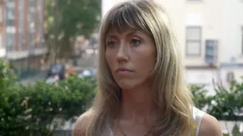 Woman with blond shoulder length hair preparing to do an interview in a London park.
