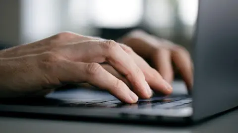 Getty Images A pair of hands on a laptop keyboard.