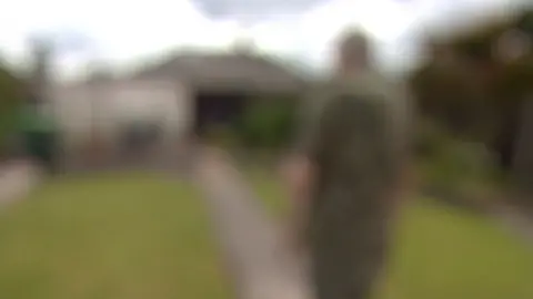 Blurred image of a man walking down a garden path