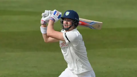 Ben McKinney looking upwards with his bat over his left shoulder