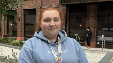 A red-headed woman in a grey hoodie.