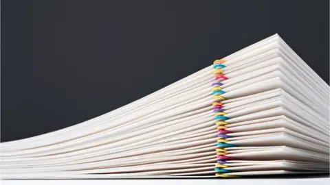 Getty/MirageC Stacked Paper Files With Colourful Paper Clips - stock photo