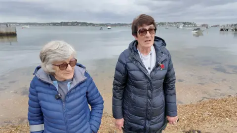 Suzanne McGowan (right) and Fanny Thomas (left) on the beach with the water behind them.