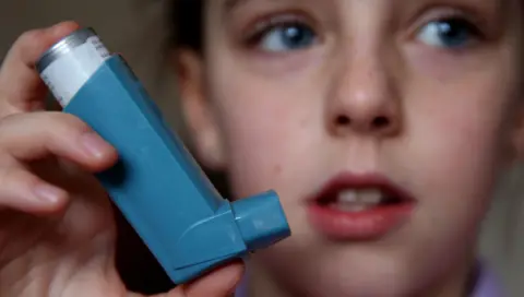 Peter Byrne/PA Media A child holding an inhaler