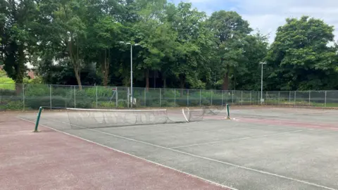 Steve Jones/BBC A tennis court with a ripped and broken net