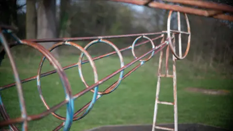 Jamie Niblock/BBC Equipment in a park's play area that is rusted in colour and worn. 