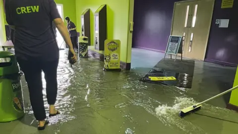 Steff Gaulter/PA Wire Staff clearing out floodwater inside The Milky Way Adventure Park in north Devon