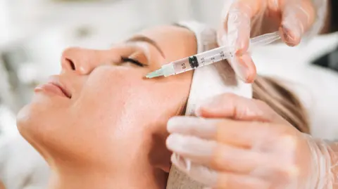 Getty Images Close-up of a woman's face as she is getting Botox injected into her cheeks.