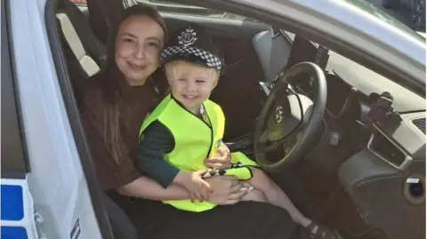 James, three, on his mum Georgia's knee in a police car