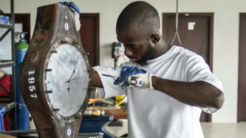 AFP A Ghanaian artist making a clock