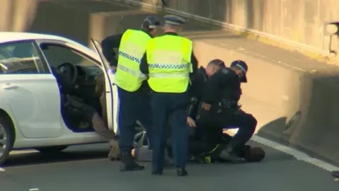 Reuters Police arrest a woman who used her car to block traffic to the Sydney Harbour Tunnel