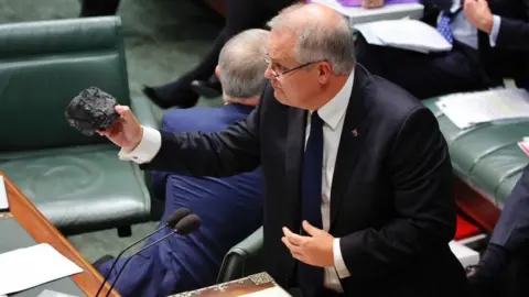 ABC News/Nick Haggarty Scott Morrison holds a lump of coal in parliament in 2017