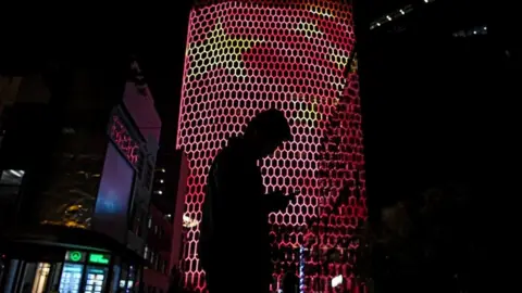 Getty Images Person on smart phone in front of Chinese flag projection