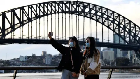 Getty Images Chinese people wearing masks take a selfie in front of the Sydney Harbour Bridge