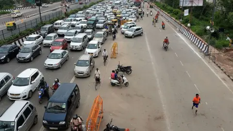 Getty Images A Kanwariya runs with a water pot in a lane reserved for devotees as traffic crawls past on 1 August 2016 in Delhi.