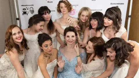 Circumpunct Studio Audrey Moore in her blue wedding dress surrounded by her friends in their old dresses