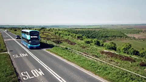 BBC Double-decker bus going through open countryside