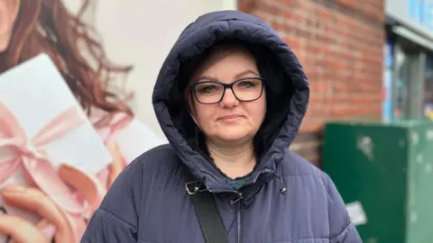 Dorata Sipos, a woman wearing glasses and a coat with the hood up.
