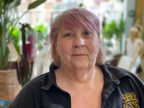 BBC/Spencer Stokes Florist Ann Fawcett wearing a black shirt with the name of her business embroidered on it