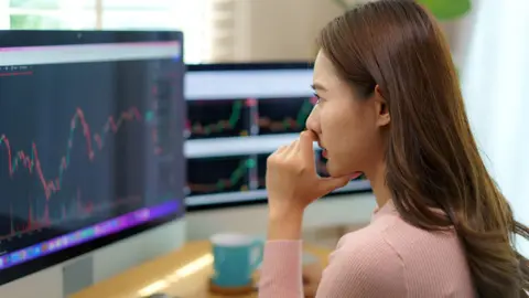 A woman looks at financial data on a computer screen in an office