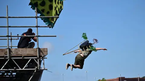 A man taking part in the Bristol Birdman competition launches himself off the end of the ramp which is on top of a scaffolding platform