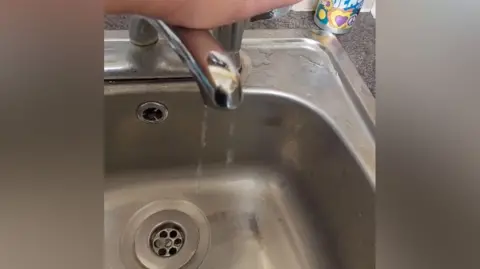 Dripping tap into a silver kitchen sink 