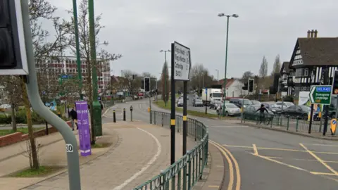 A google street view of a main road with cars on the far right hand side of the road