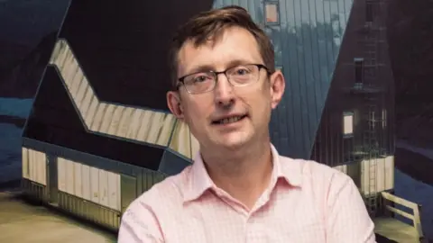 Shaun West Shaun West in a pink shirt and spectacles
