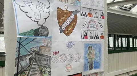 NEXUS More artwork on another banner. One of these drawings depicts eight people behind bars, representing the eight striking miners who were sentenced to prison for their role in derailing the Flying Scotsman, which happened after lines were sabotaged to stop a coal train reaching its destination.