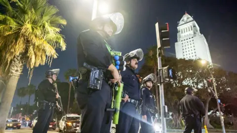 Police officers in riot gear stand near City Hall as a curfew is in effect following days of protests in response to federal immigration operations in Los Angeles on June 10, 2025.