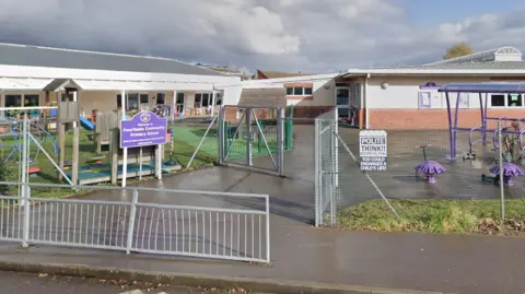 Google Street view of the school with metal railings in front and a purple board with the school name 