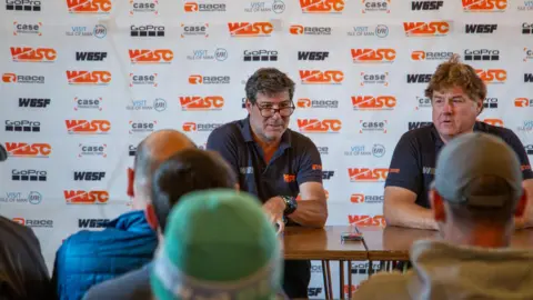 WDSC Selim Kemahli, who has dark hair and wears a dark polo shirt, appears behind a table at a press conference.