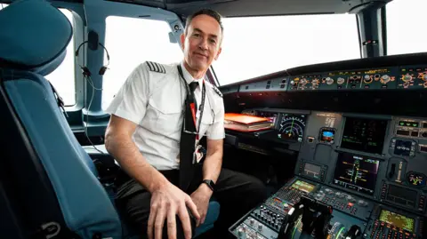 EasyJet David smiles at the camera while sitting in the cockpit of the plane.
