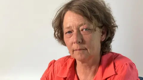 Wearing a red blouse, Samantha Gillingham stares into the camera.