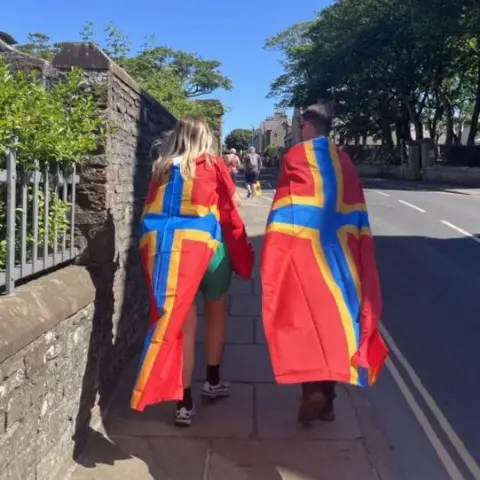 Two people with Orkney flags draped over them