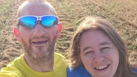 Family handout A selfie image of Ben Jacobs and his wife Faye. Ben is wearing sunglasses and a yellow top while Fay is wearing a blue T-shirt. They are both smiling and looking into the camera.